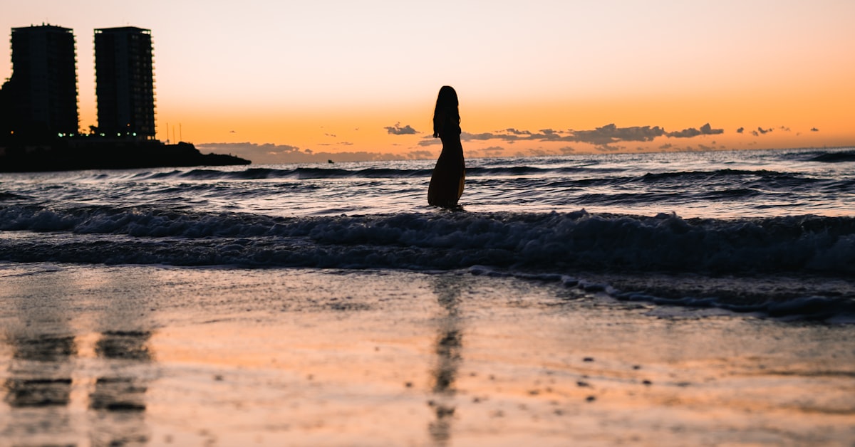Silhouette einer Frau am Strand bei Sonnenuntergang, Symbolbild für Neuanfang nach Liebeskummer