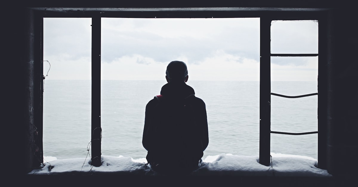 Person schaut aus dem Fenster und wartet, Symbolbild für Hoffen bei unerwiderter Liebe